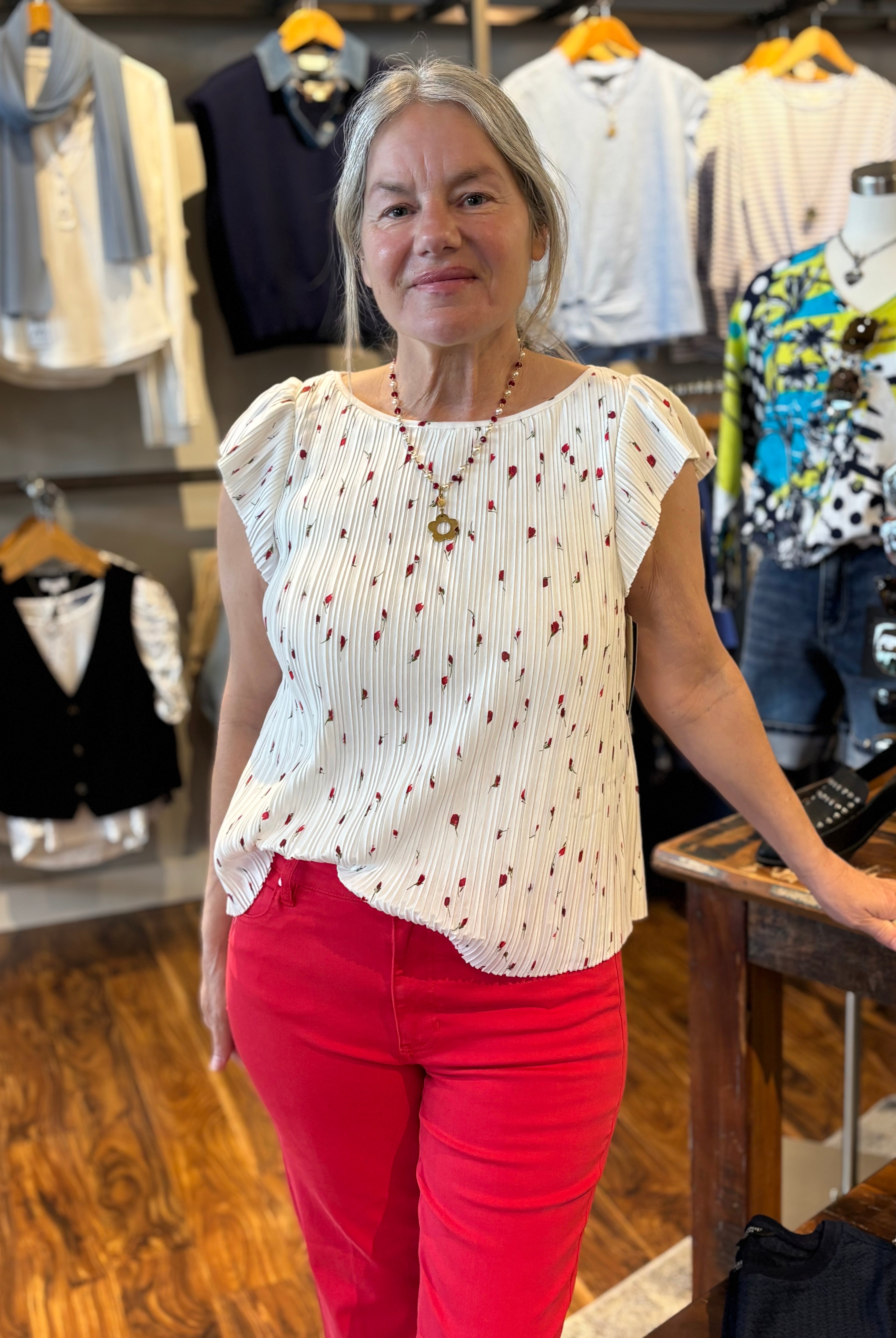 Woman in a store wearing a white blouse with red flowers