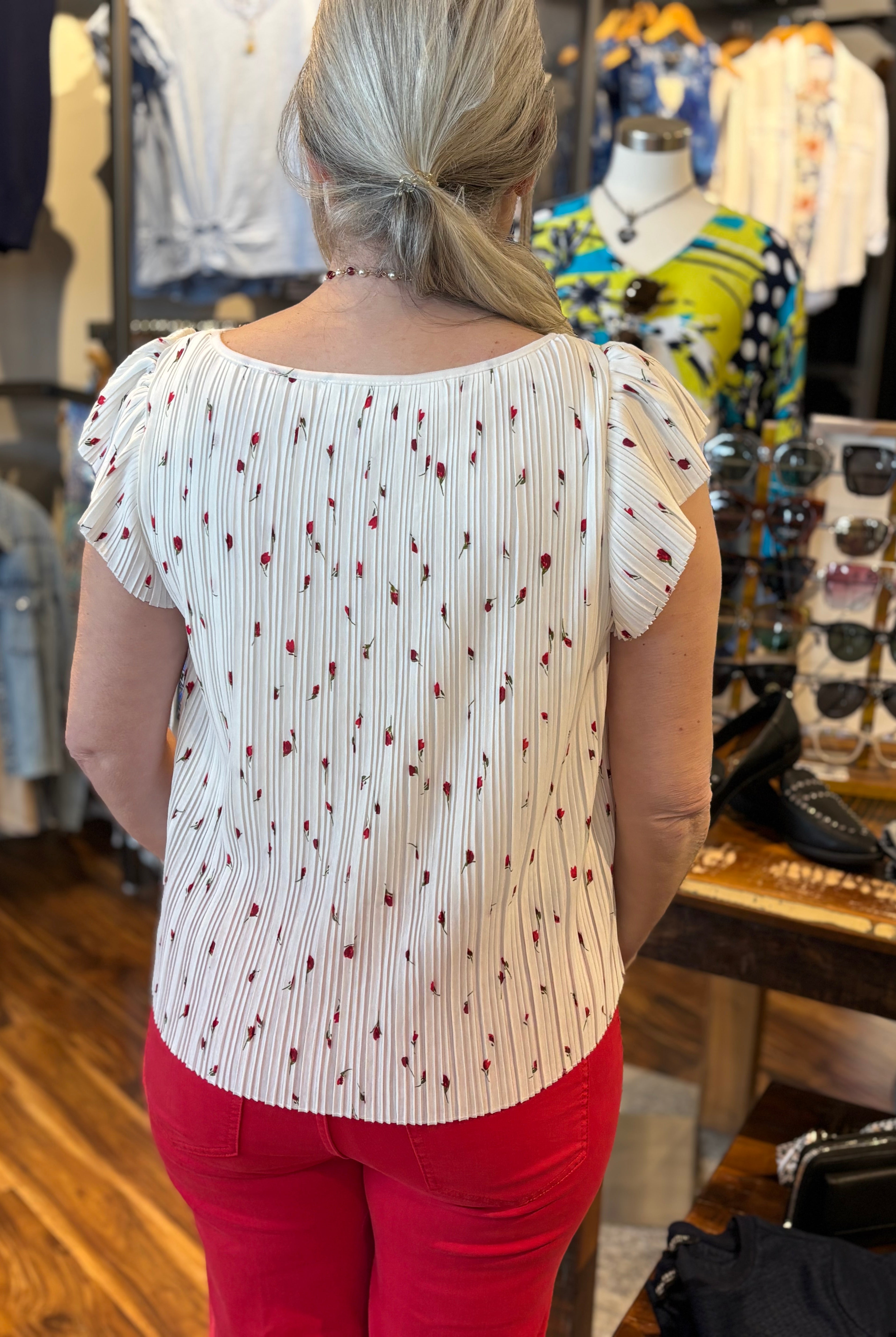 Woman wearing a white blouse with red small red flowers with green stems