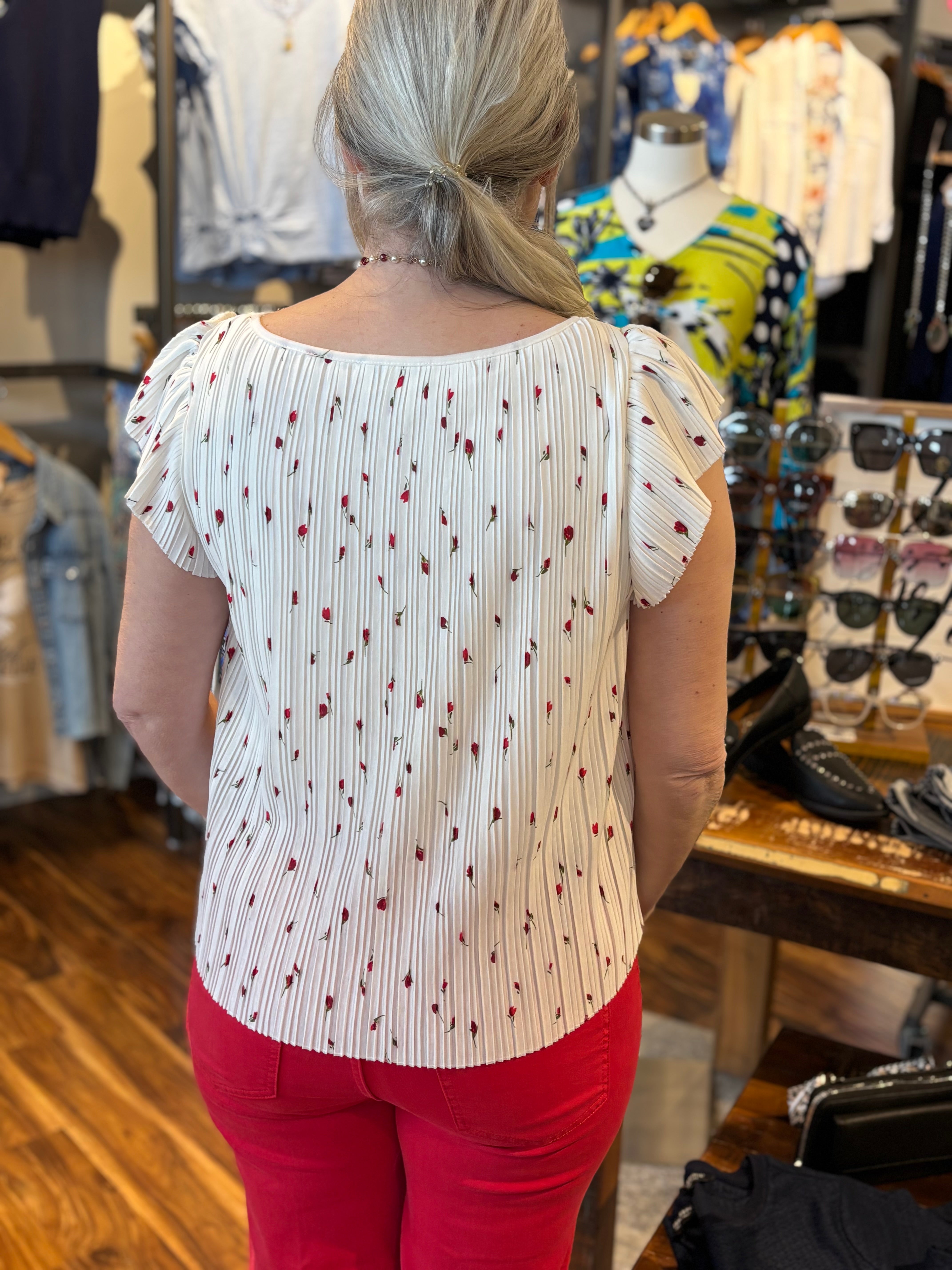 Woman wearing a white blouse with red small red flowers with green stems
