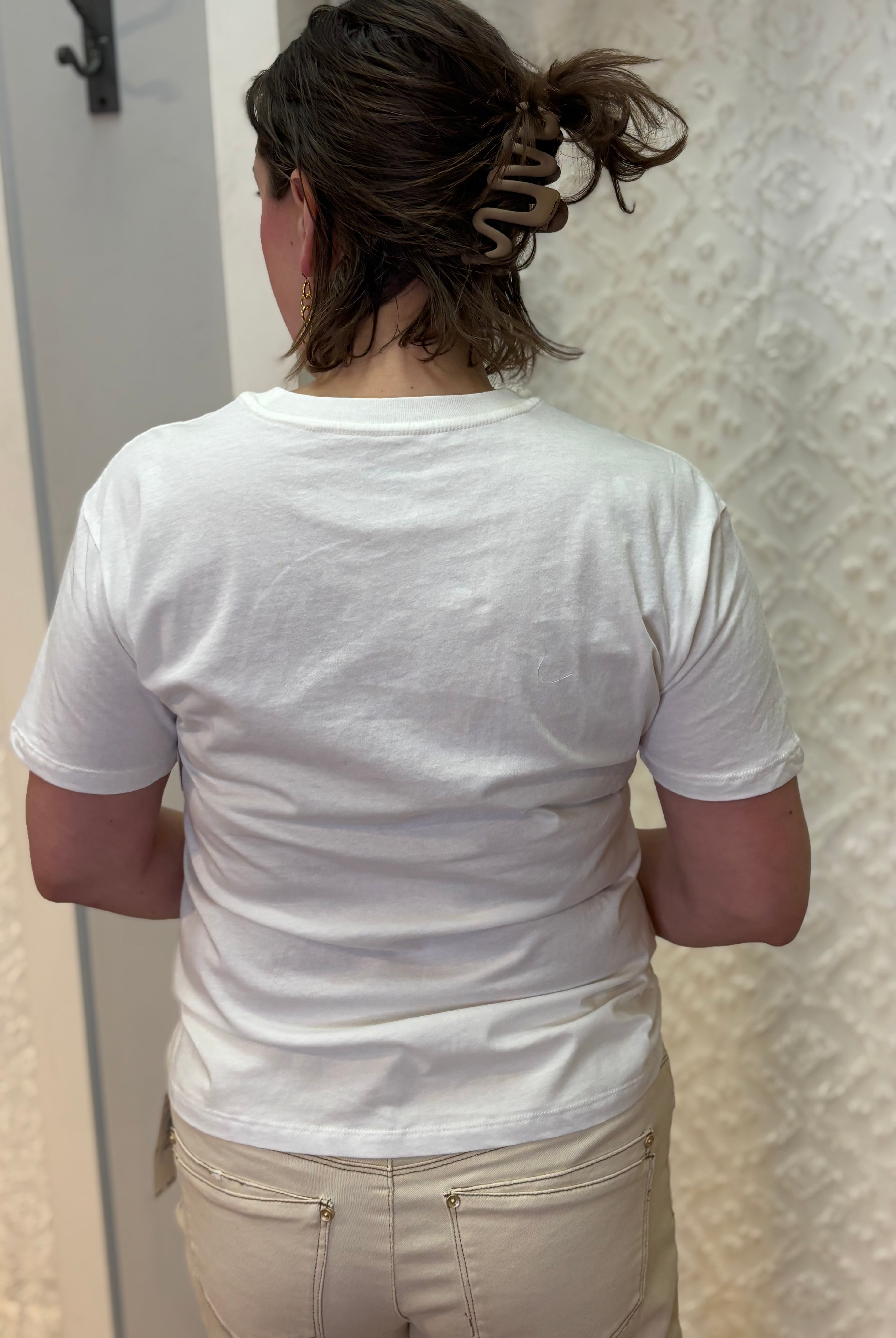 Woman wearing white boyfriend-fit tee shirt with green palm trees pattern on front