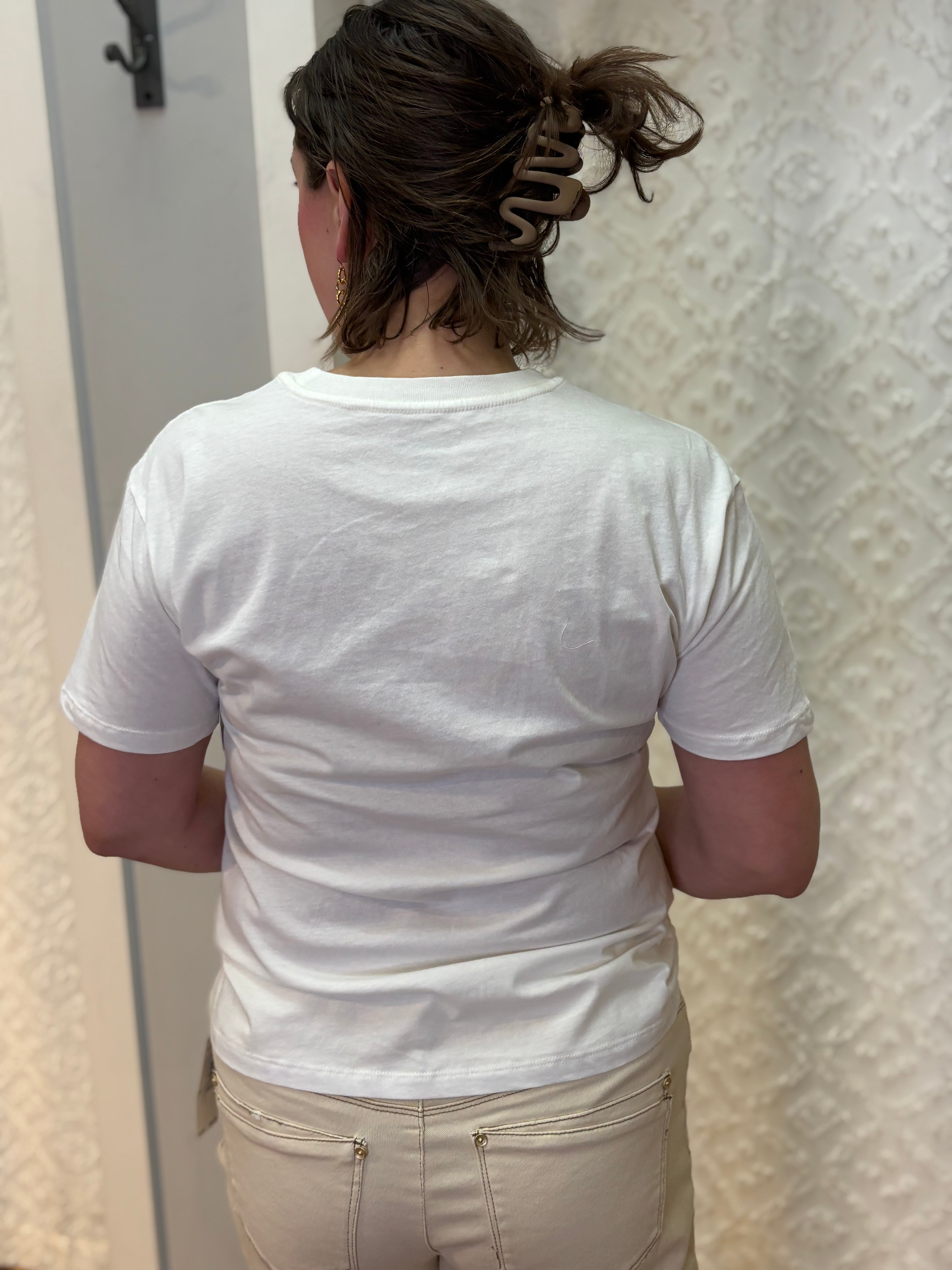 Woman wearing white boyfriend-fit tee shirt with green palm trees pattern on front