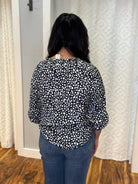 Person wearing black v-neck polyester blouse with small white asymmetrical hearts