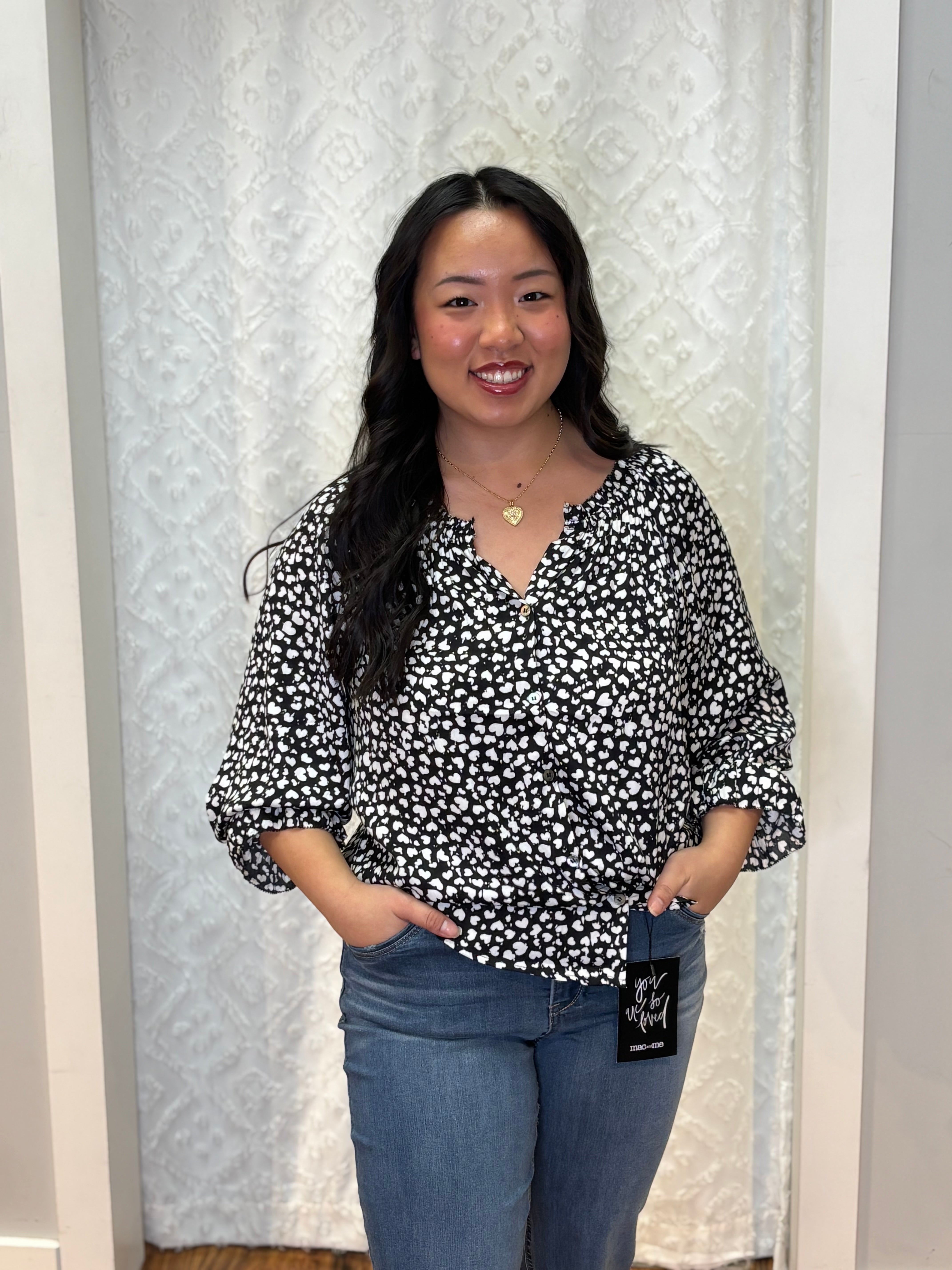 Person wearing black v-neck polyester blouse with small white asymmetrical hearts