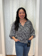 Person wearing black v-neck polyester blouse with small white asymmetrical hearts