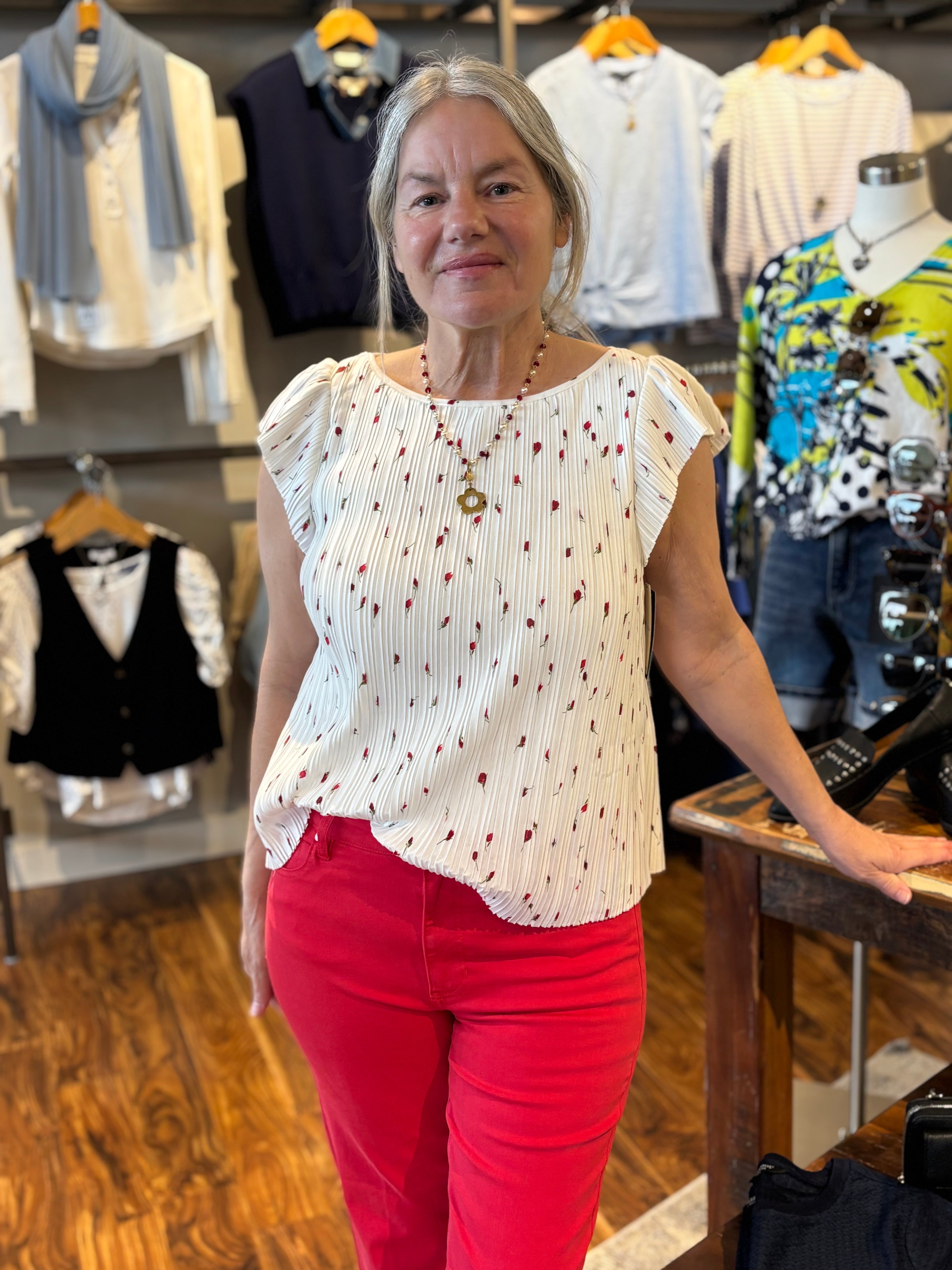 Woman in a store wearing a white blouse with red flowers
